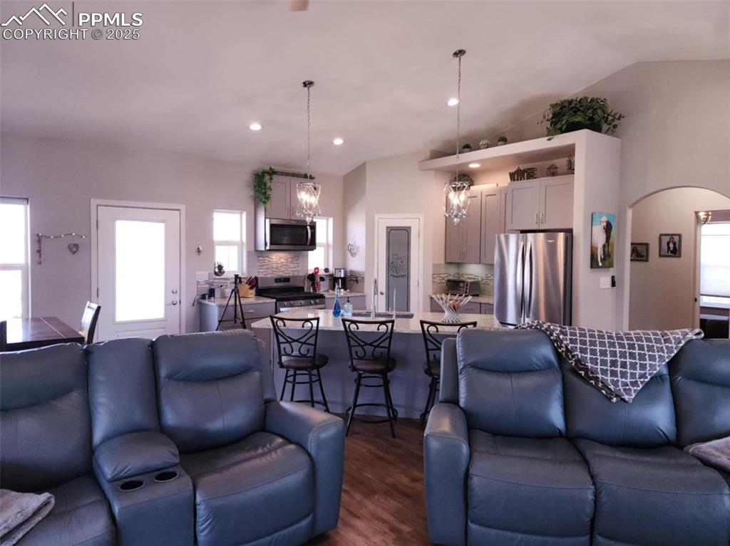 Image 13 of 47: Living area with arched walkways, dark wood finished floors, lofted ceiling
