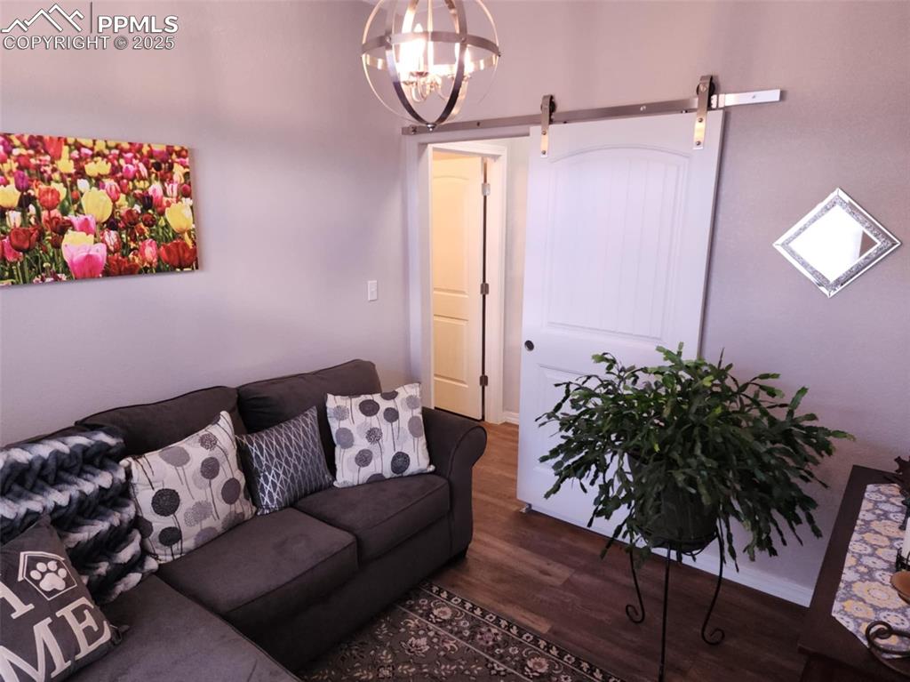 Image 22 of 47: Living area with a barn door, dark wood-type flooring, and a chandelier