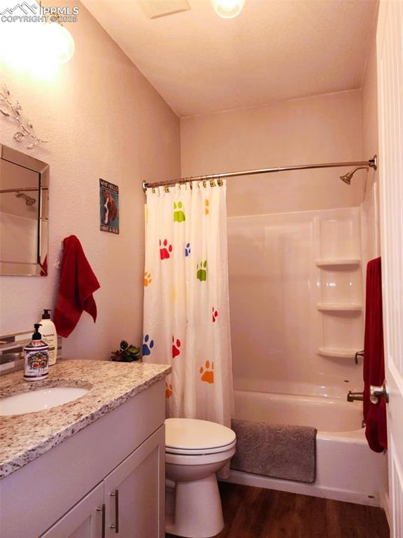Image 24 of 47: Bathroom featuring shower / tub combo, vanity, and dark wood-style flooring