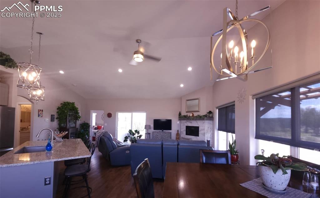Image 4 of 47: Dining area featuring a chandelier, vaulted ceiling, ceiling fan, dark wood