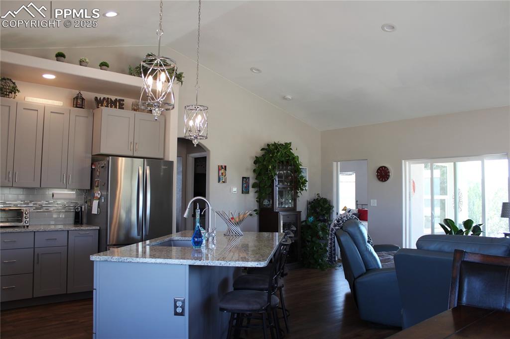 Image 6 of 47: Kitchen with gray cabinetry, freestanding refrigerator, open floor plan, de