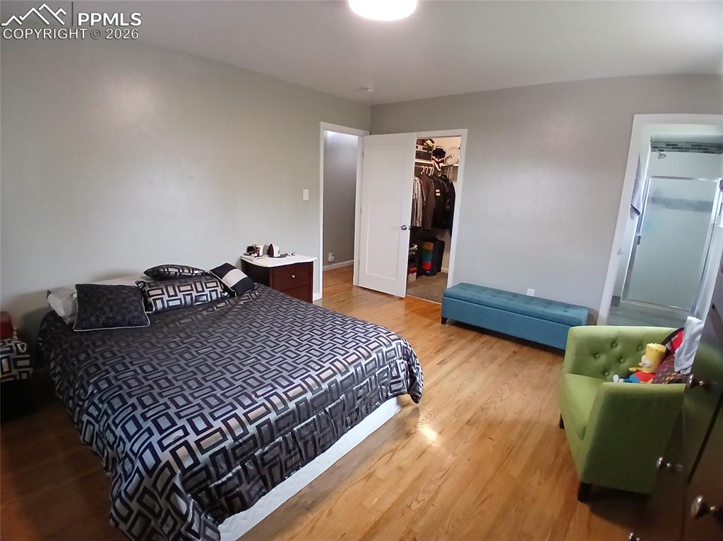 Image 23 of 49: Bedroom with a walk in closet, a closet, and hardwood / wood-style floors