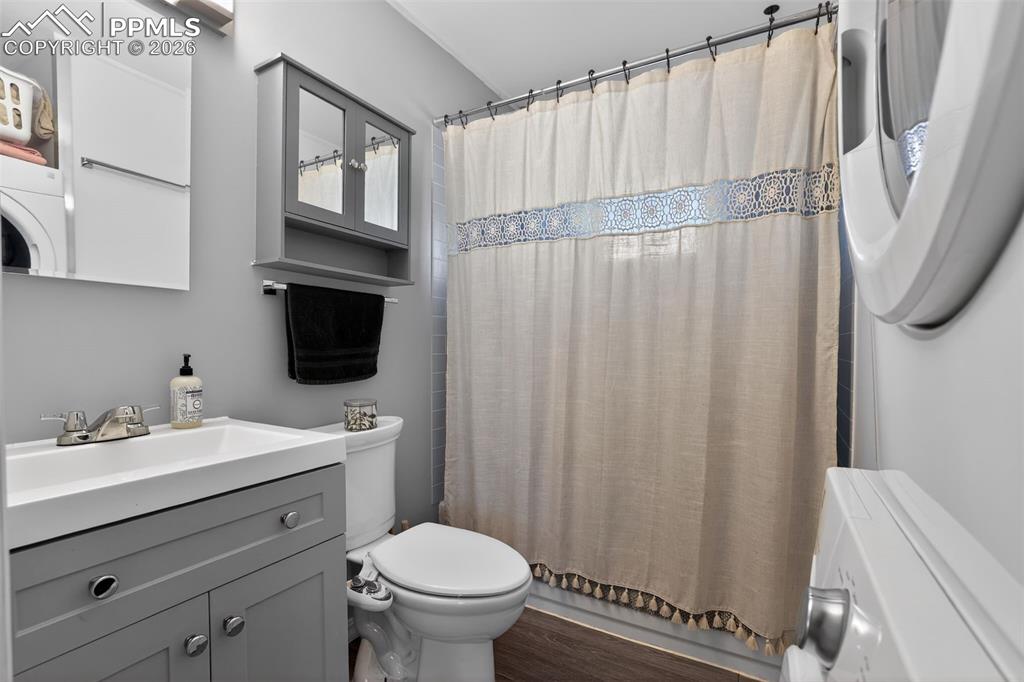 Image 4 of 15: Bathroom featuring vanity, dark wood-style flooring, and washer / clothes d