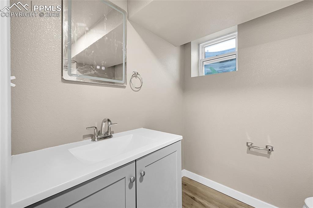 Image 10 of 15: Bathroom with vanity, light wood-type flooring, and a textured wall