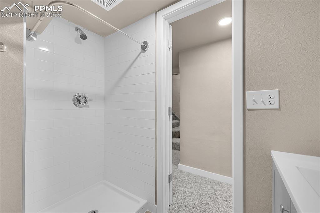 Image 11 of 15: Full bath with a shower stall, vanity, and a textured wall