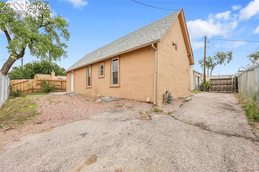 Image 2 of 15: Rear view of house featuring a fenced backyard, stucco siding, and roof wit