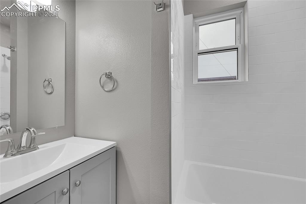Image 6 of 15: Bathroom with vanity, a textured wall, and bathtub / shower combination
