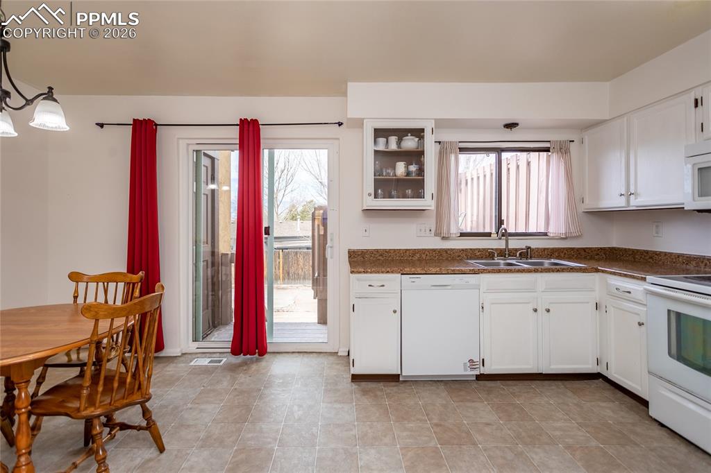Image 13 of 30: Kitchen featuring white cabinetry, white appliances, decorative light fixtu