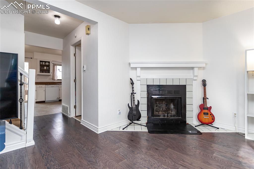 Image 8 of 30: Living area featuring wood finished floors and a tiled fireplace