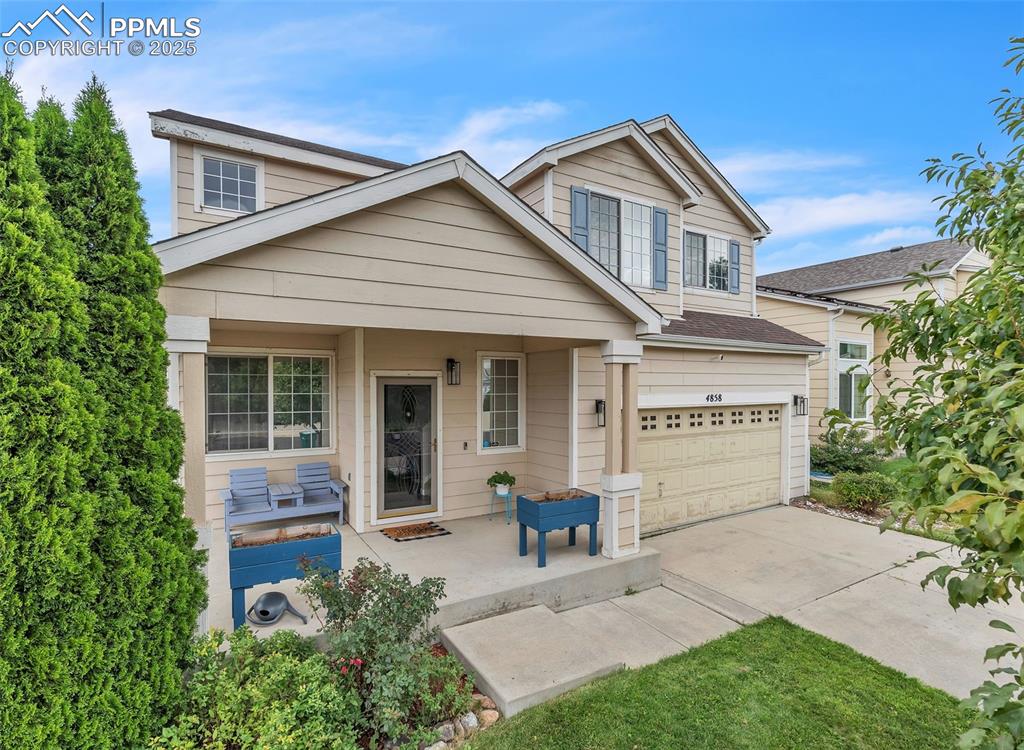 Caption: Traditional-style home featuring a porch, a garage, and driveway