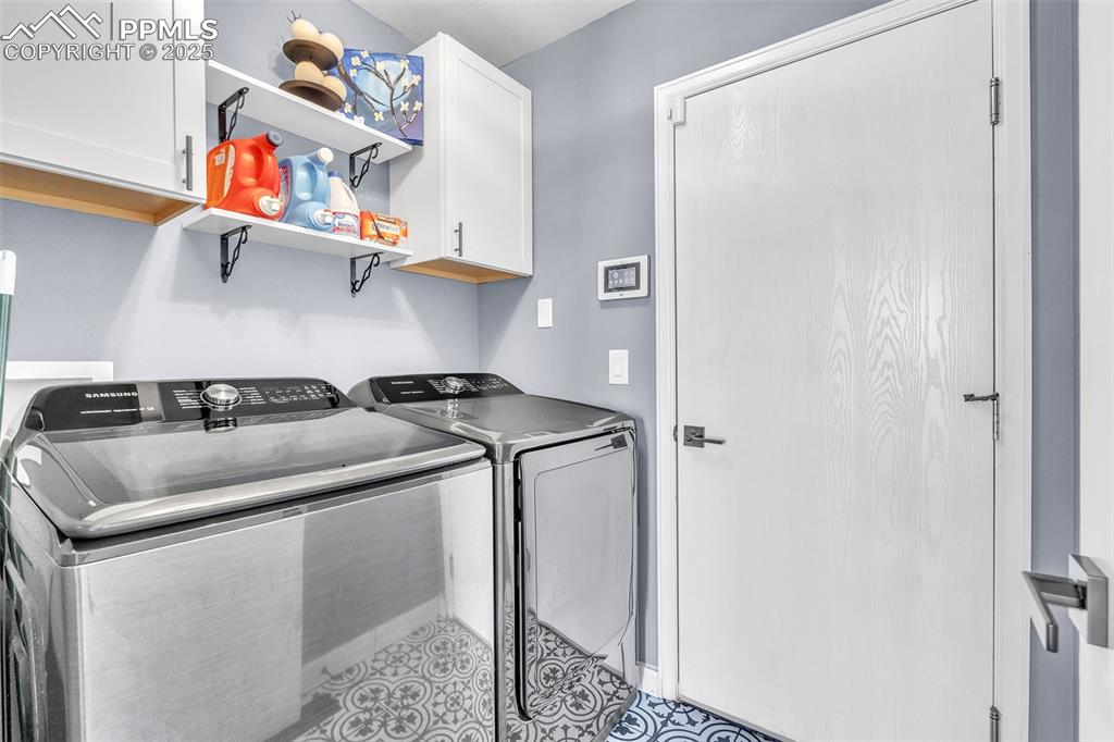 Image 11 of 26: Washroom featuring cabinet space, washer and clothes dryer, and tile patter