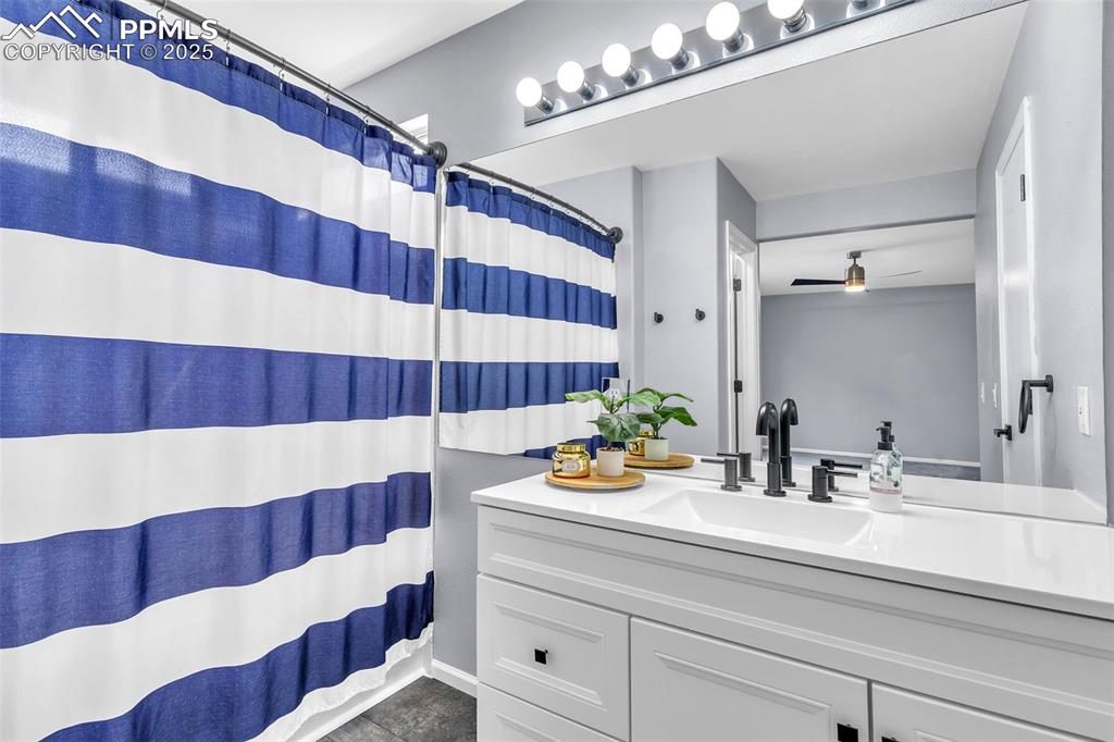 Image 20 of 26: Full bathroom featuring vanity, ceiling fan, and dark tile patterned floors
