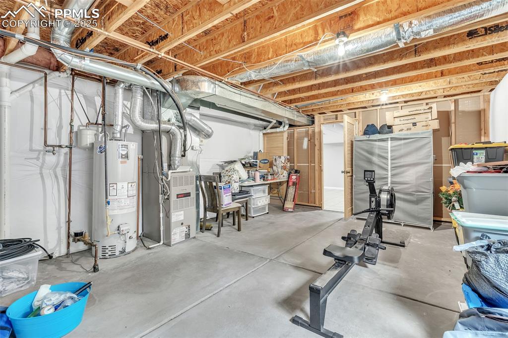 Image 24 of 26: Unfinished below grade area featuring gas water heater and heating unit