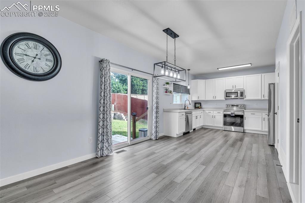 Image 7 of 26: Kitchen featuring white cabinetry, light countertops, appliances with stain