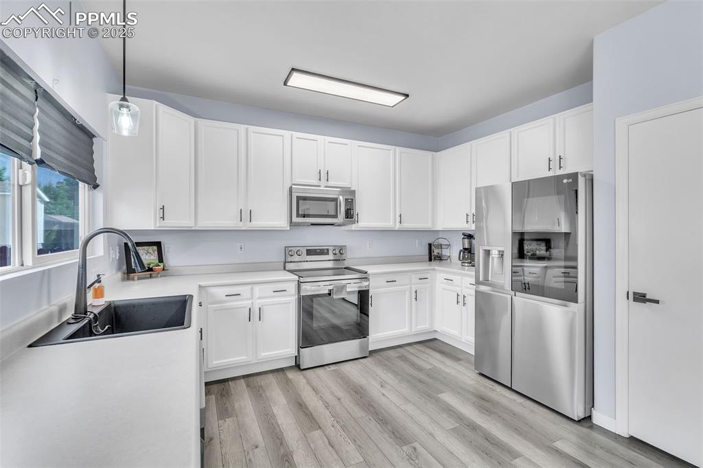 Image 8 of 26: Kitchen featuring stainless steel appliances, light countertops, and white 