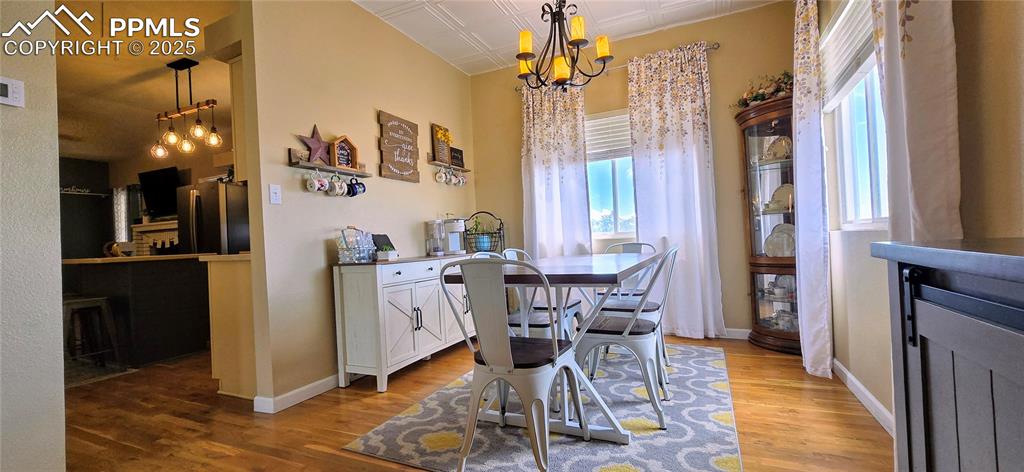 Image 11 of 48: Dining room featuring wood finished floors, a chandelier, and an ornate cei