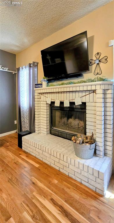 Image 19 of 48: Detailed view of a textured ceiling, wood finished floors, and a brick fire