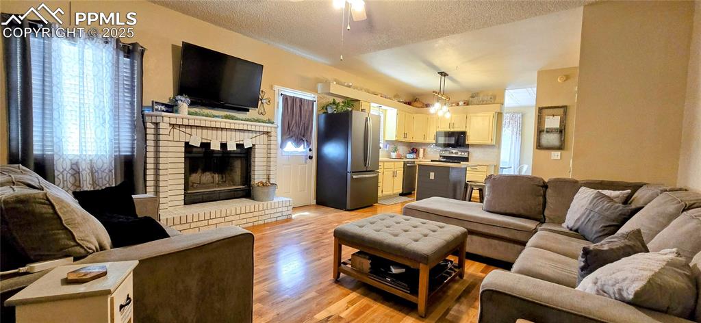 Image 22 of 48: Living area featuring light wood-style floors, a fireplace, and a textured