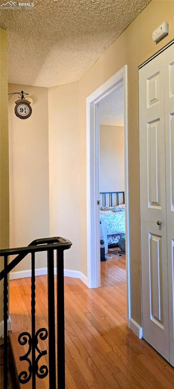 Image 27 of 48: Corridor with light wood-style floors and a textured ceiling
