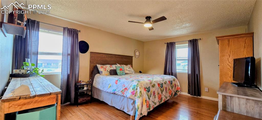 Image 28 of 48: Bedroom with light wood-style floors, a ceiling fan, and a textured ceiling