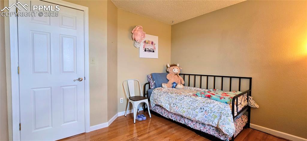 Image 32 of 48: Bedroom featuring a textured ceiling and wood finished floors
