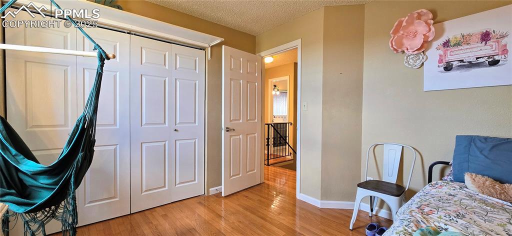 Image 33 of 48: Bedroom with a textured ceiling, a closet, and light wood-style flooring