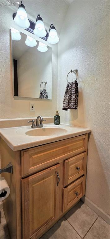Image 40 of 48: Bathroom featuring a textured wall, vanity, and light tile patterned floors