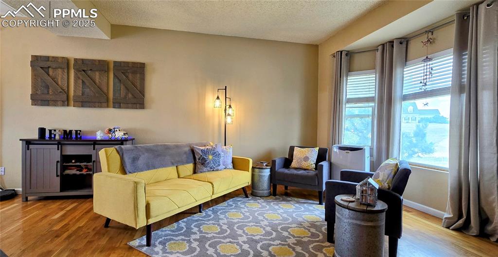 Image 8 of 48: Living area featuring a textured ceiling and wood finished floors