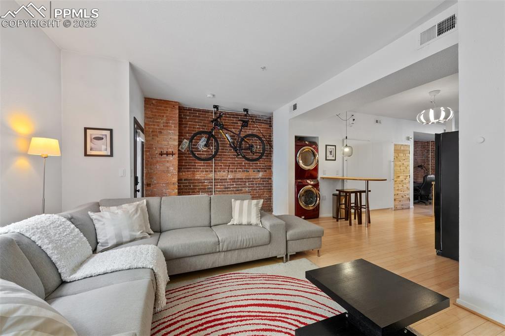 Image 11 of 26: Living room with visible vents, stacked washing maching and dryer, light wo