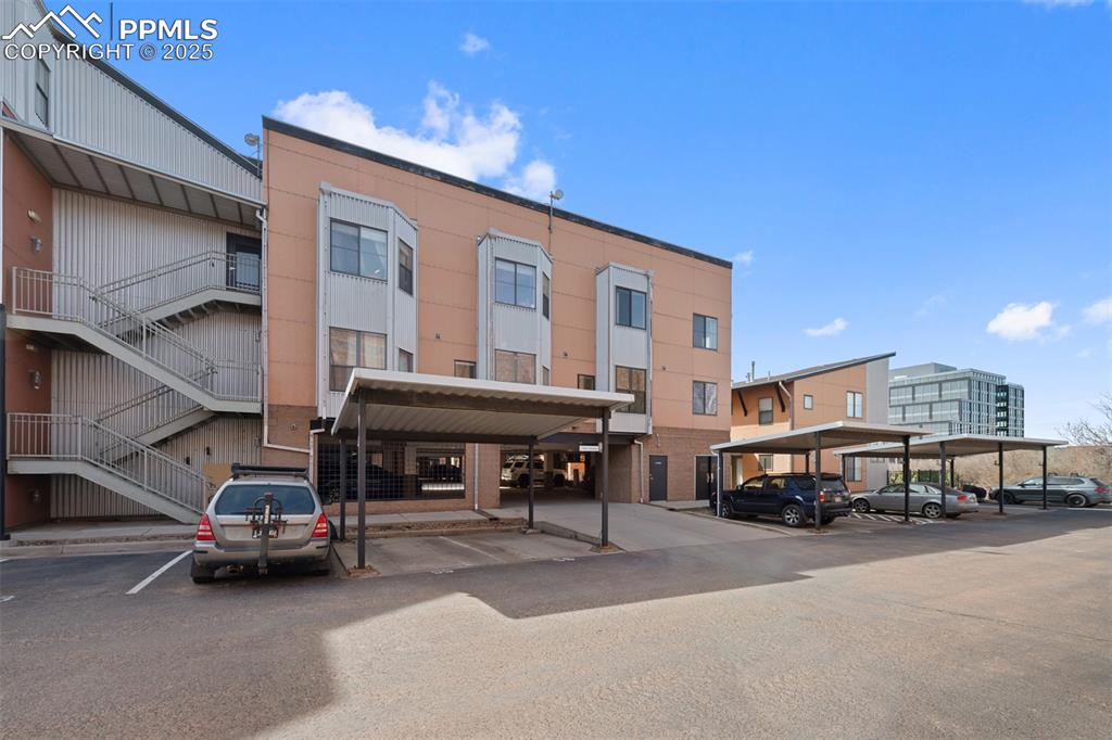 Image 24 of 26: View of building exterior with stairway and covered and uncovered parking