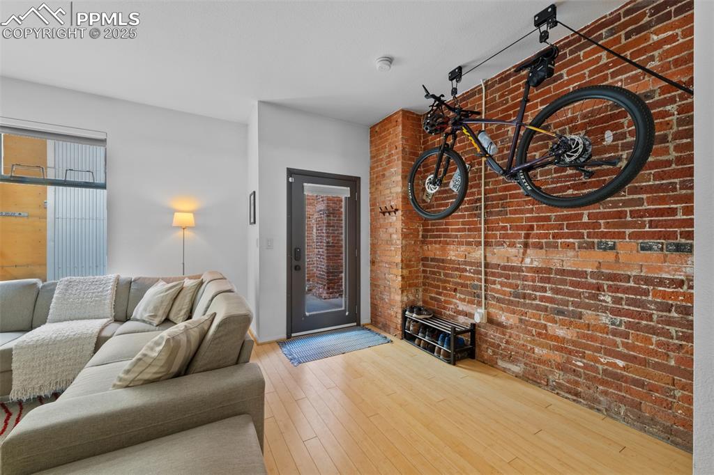 Image 7 of 26: Living room with hardwood / wood-style flooring and brick wall
