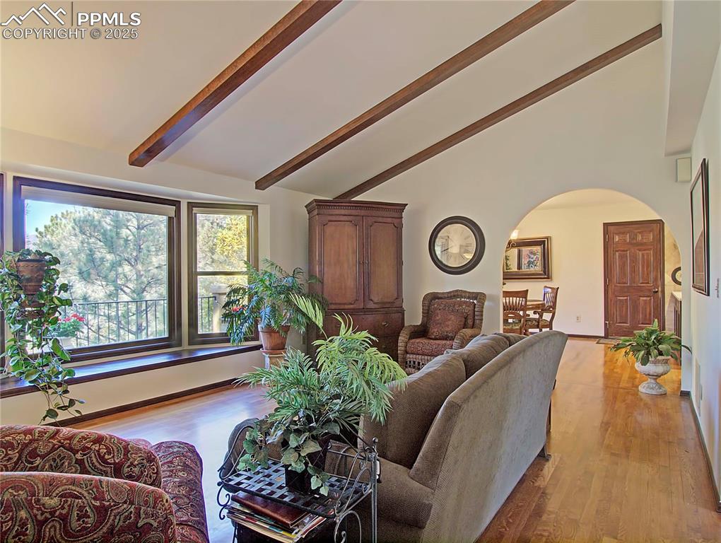 Image 11 of 41: Living room with arched walkways, light wood-style flooring, beam ceiling, 