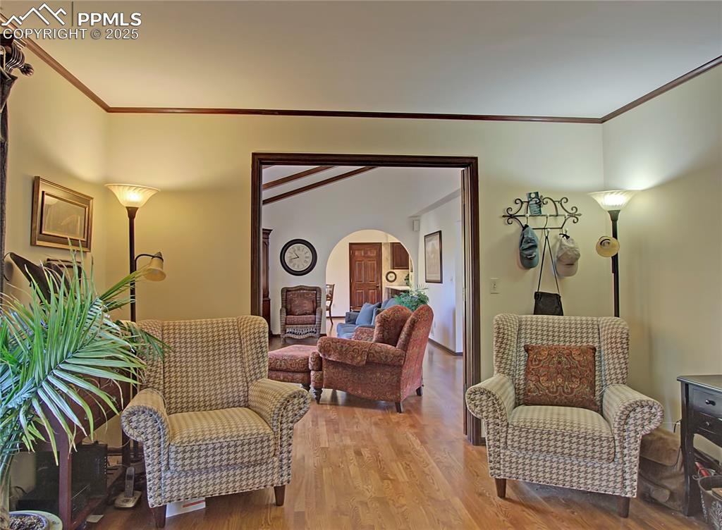 Image 17 of 41: Living area featuring arched walkways, light wood-style floors, crown moldi