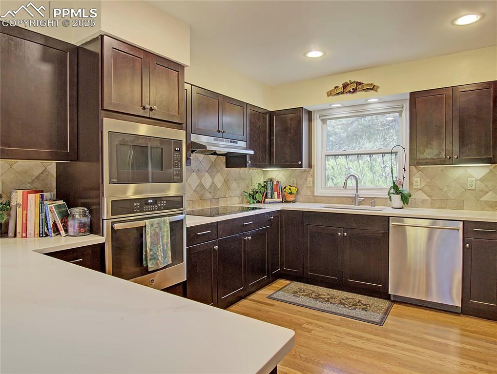 Image 22 of 41: Kitchen featuring dark brown cabinetry, appliances with stainless steel fin