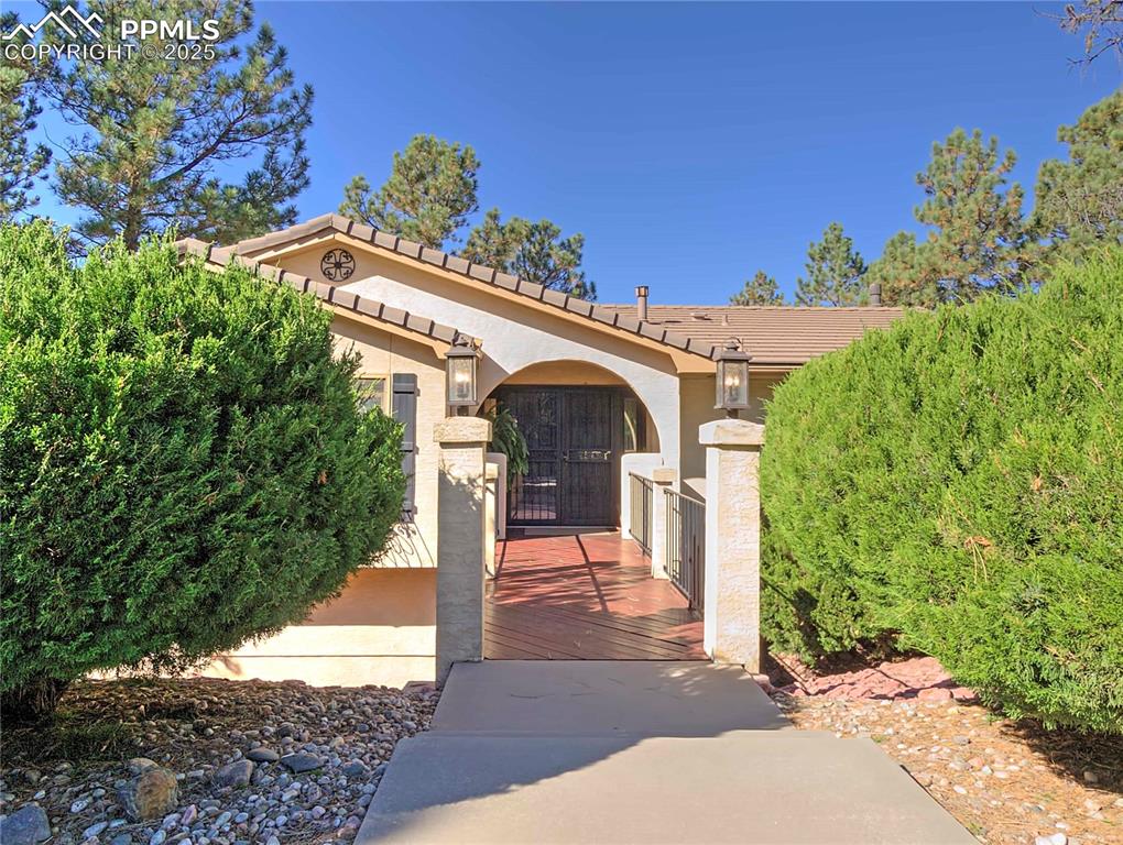 Image 3 of 41: Doorway to property with a tile roof and stucco siding