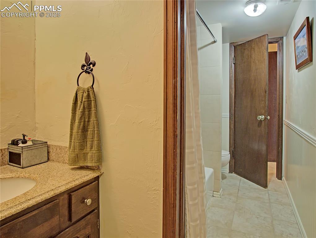 Image 32 of 41: Bathroom with a textured wall, vanity, a shower stall, and light tile patte