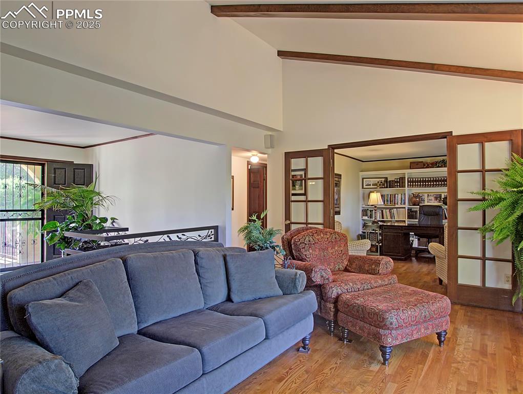 Image 9 of 41: Living room with wood finished floors, high vaulted ceiling, and beam ceili