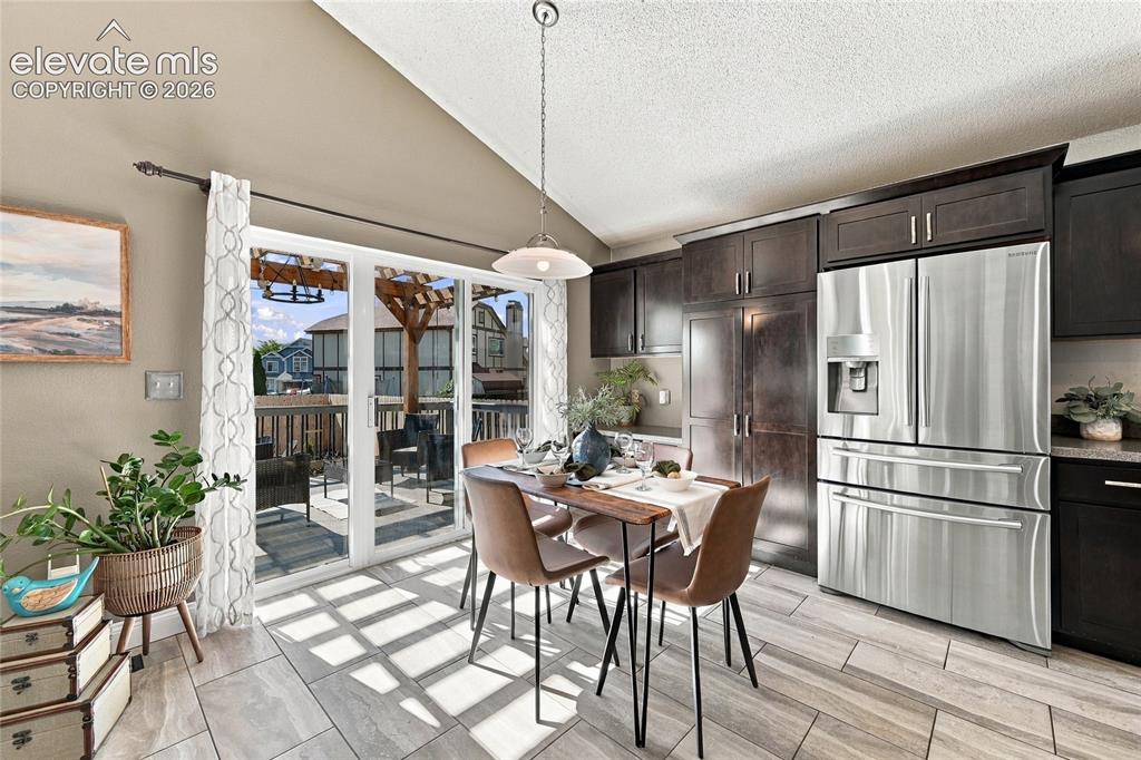 Image 10 of 45: Kitchen with vaulted ceiling, dark wood cabinetry, stainless steel French d