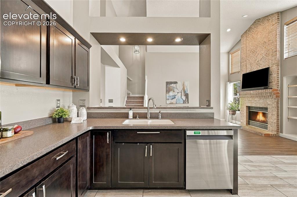 Image 13 of 45: Kitchen featuring dark wood cabinetry, solid surface countertops, a stainle