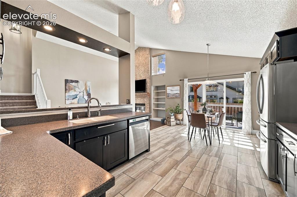 Image 15 of 45: Kitchen featuring dark cabinetry, stainless steel appliances, and a built-i