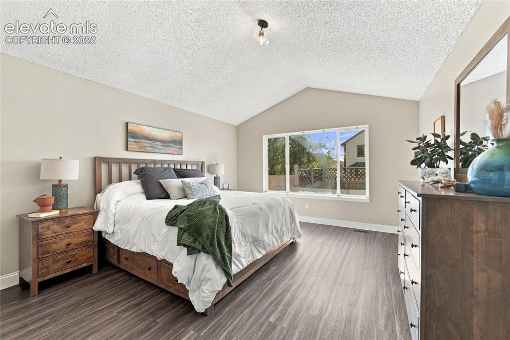 Image 18 of 45: Vaulted ceiling, wood look vinyl plank flooring, large window, and light-to