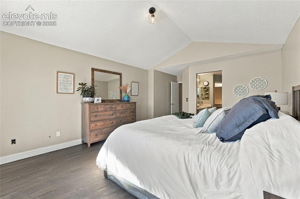 Image 20 of 45: Primary bedroom featuring vaulted ceilings, wood look vinyl plank flooring,