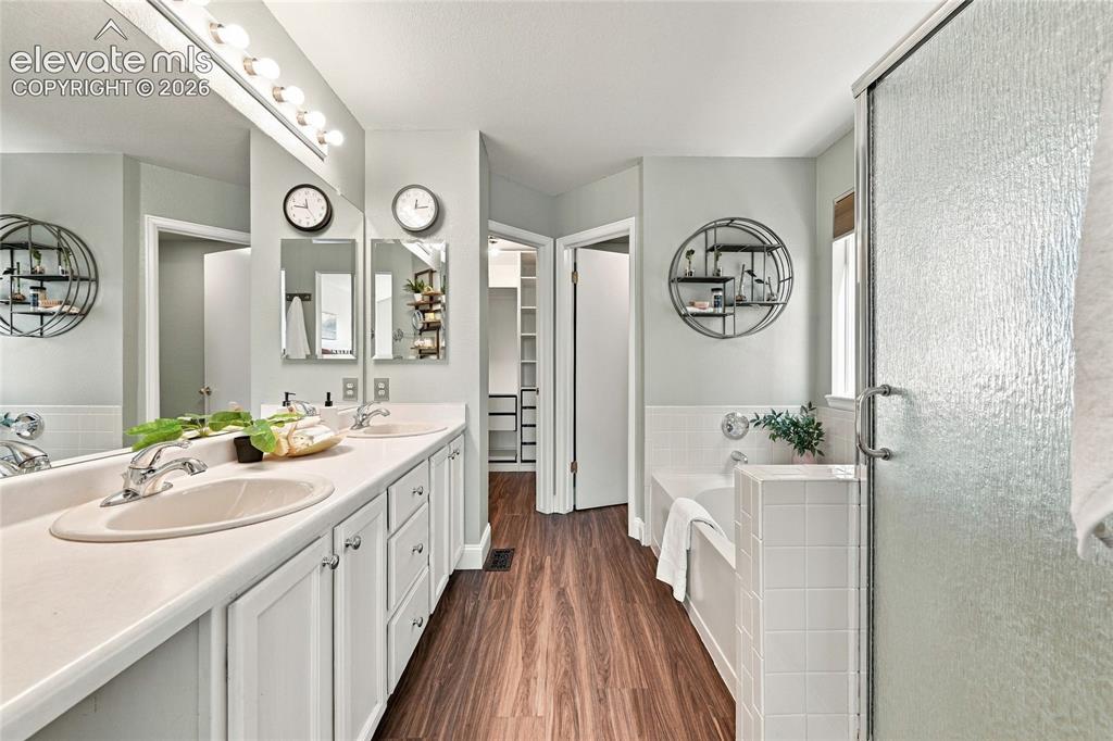 Image 21 of 45: Dual vanity with white cabinetry, wood look vinyl plank flooring, built-in 