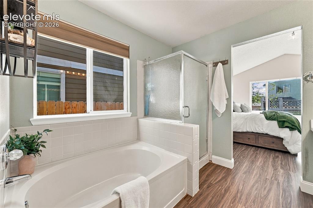 Image 22 of 45: Soaking tub with white tile surround, adjacent to a glass-enclosed shower