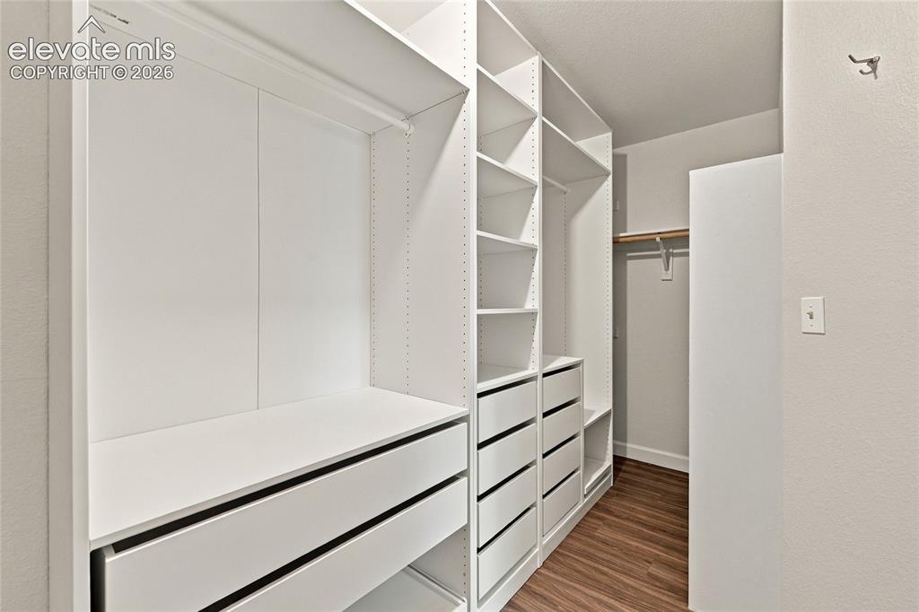 Image 23 of 45: Custom closet system featuring white built-in shelving, multiple drawers, a