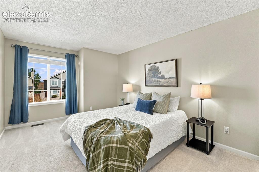 Image 27 of 45: Bright bedroom featuring dual nightstands with integrated lighting, a large