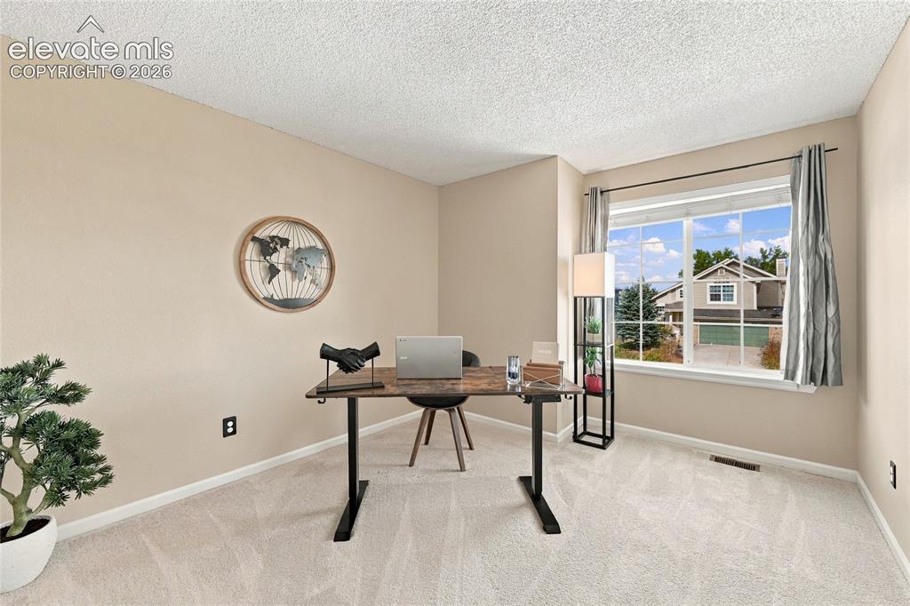Image 29 of 45: Bright home office/bedroom featuring a large picture window with natural li
