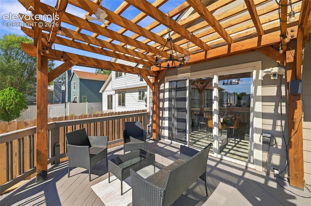 Image 33 of 45: Outdoor deck with a wooden pergola, sliding glass door access, and a built-