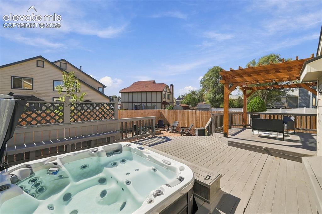 Image 34 of 45: Expansive multi-level deck featuring a built-in hot tub, wood pergola, and 