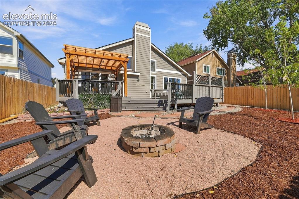 Image 35 of 45: Exterior featuring a rear deck with a pergola, a fire pit, and a fenced yar